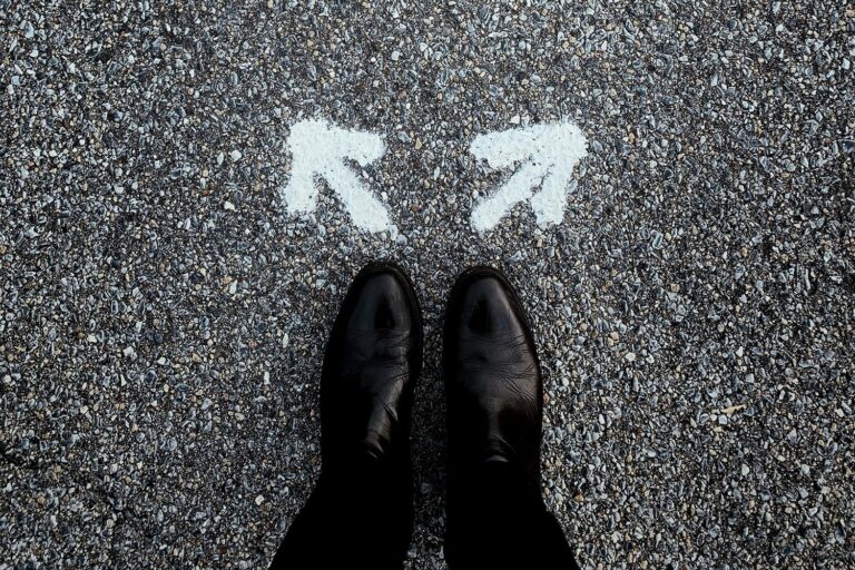 Person standing in front of two arrows on the ground, each going different directions