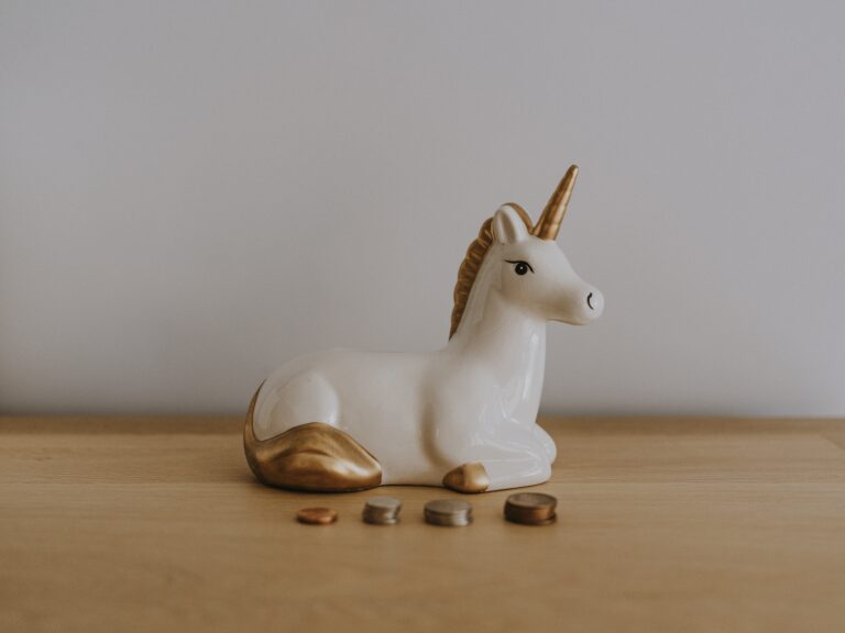 a unicorn figurine sitting next to coins