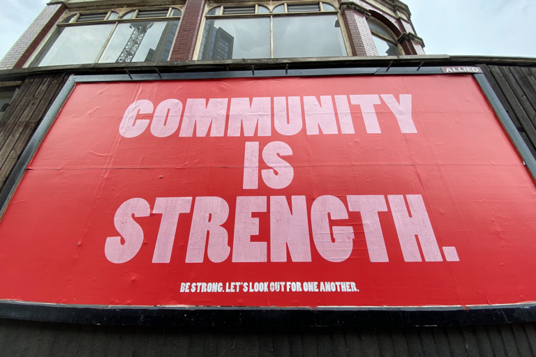 Billboard text reads: Community is Strength. Be Strong. Look out for one another.