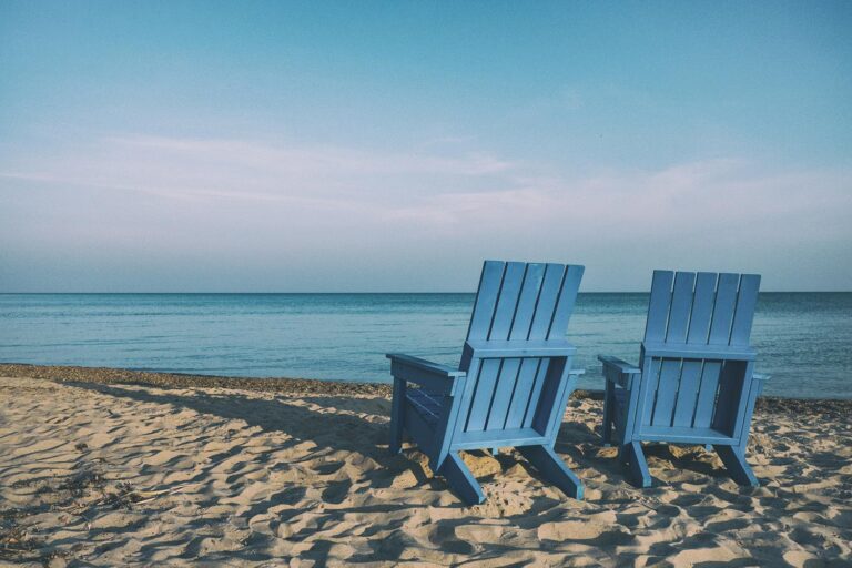 Two wood beach chairs at the ocean