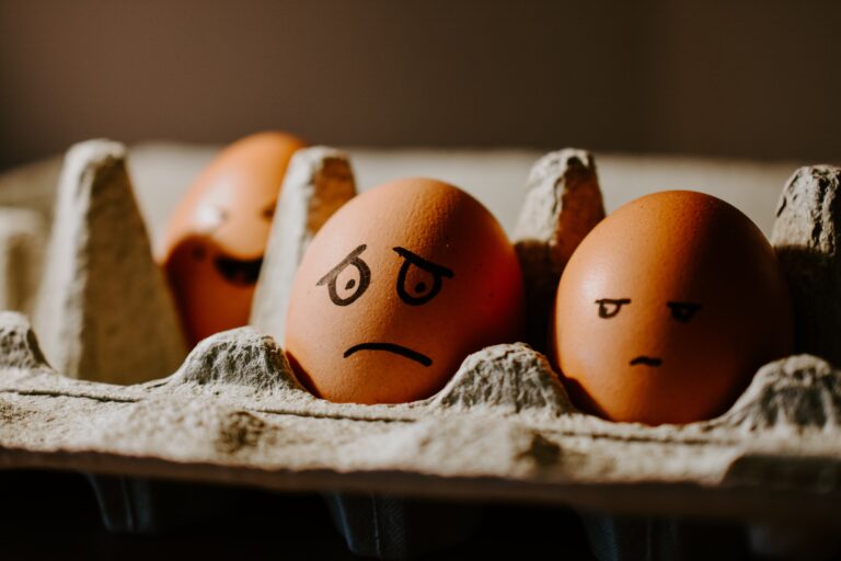 two eggs in a carton with concern facial expressions drawn on with marker