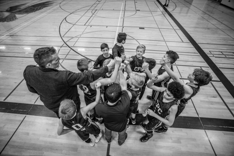 a coach and children's basketball team in a huddle