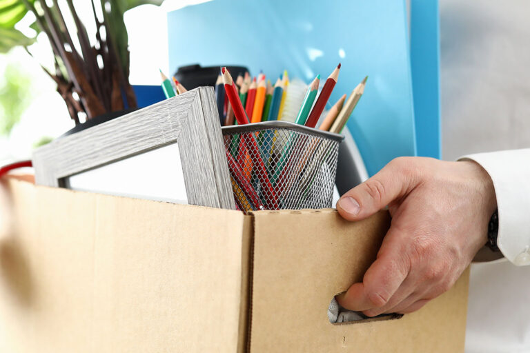 close-up of a person carrying a box of items from an office desk