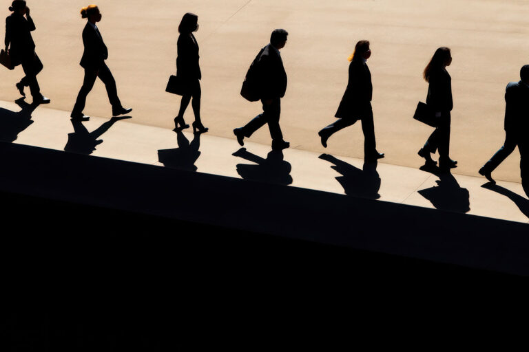 a silhouette of a line of business people walking on a platform