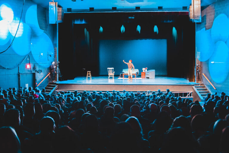 a person performs on a stage with an audience watching