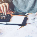 a person using an adding machine holding papers