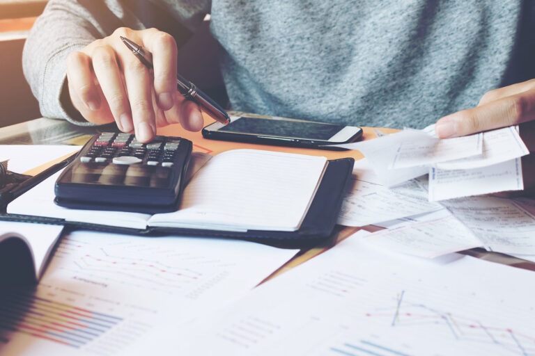 a person using an adding machine holding papers