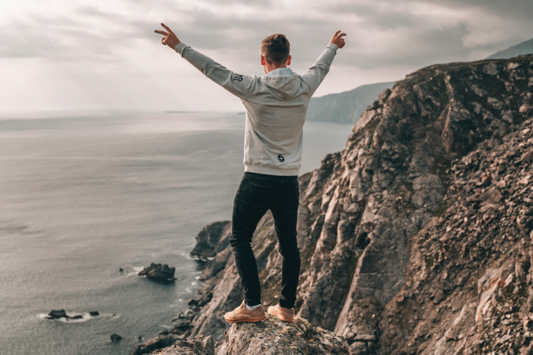 Man standing at the top of an ocean-front cliff