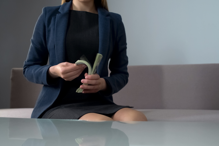 Businesswoman flips through wad of 100 dollar bills