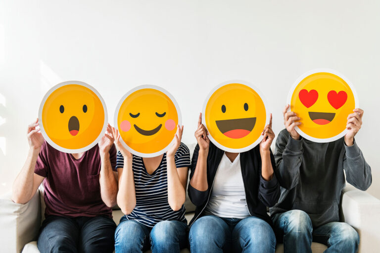 four people holding up emoticons in front of their faces