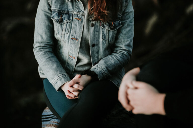 two people sitting and talking, shown from chest down