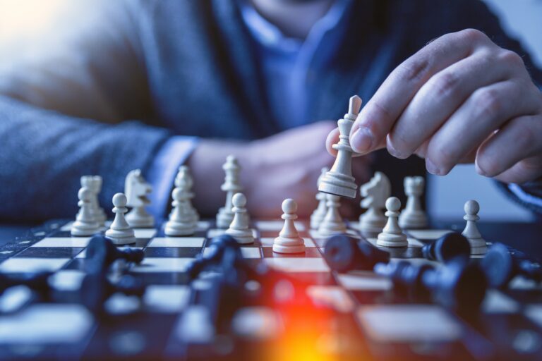 closeup of a chess boards with a man holding a chess piece