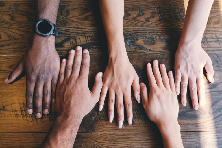 Five different hands coming together on a table