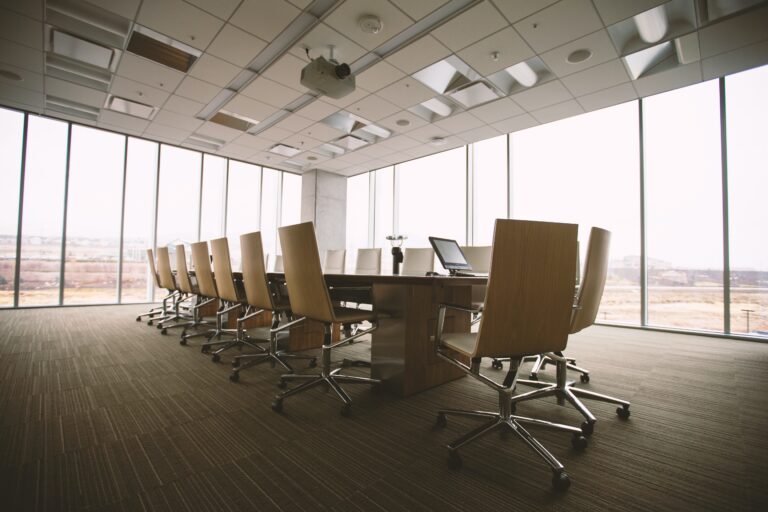 a room with a large table and many office chairs surrounding