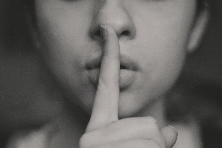 Woman with finger on lips, meant to signal be quiet