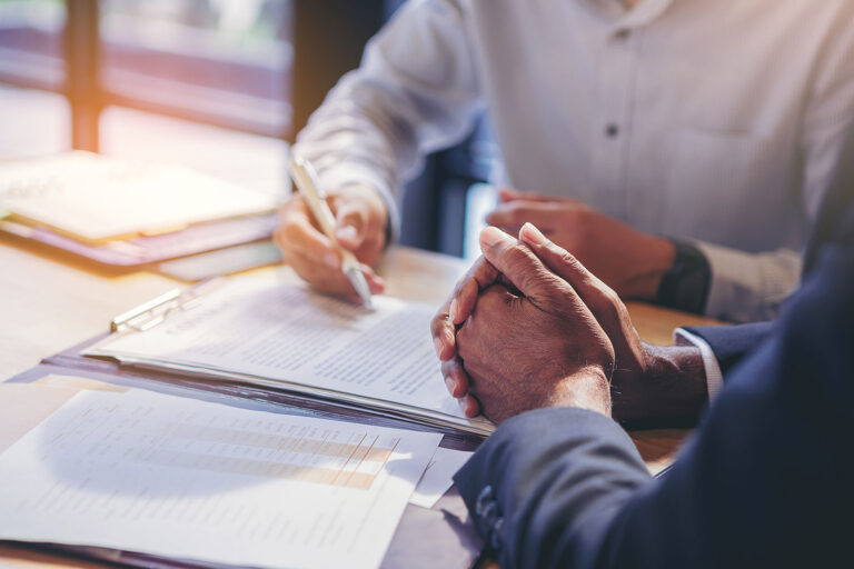 two people sitting at a desk signing papers