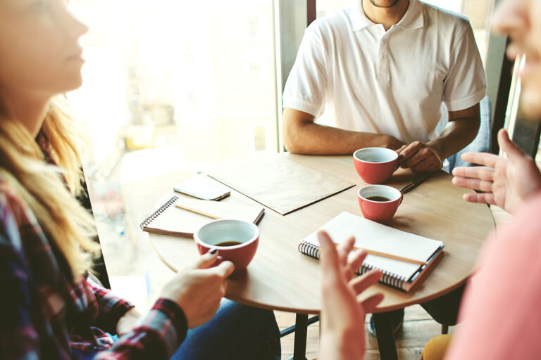 people at a table drinking coffee and talking business