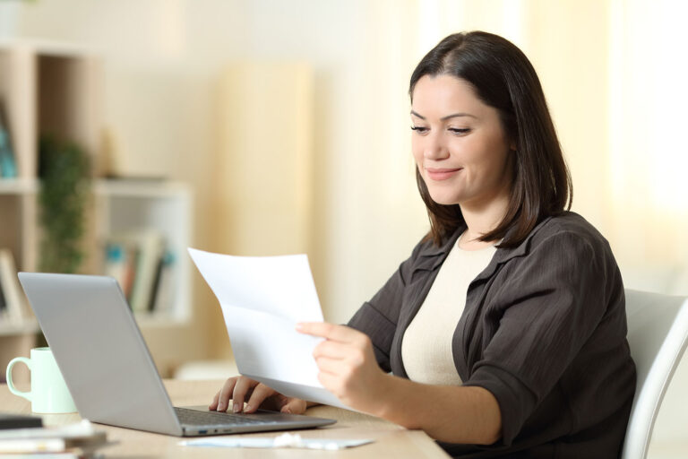 a woman sitting at a laptop reads a letter