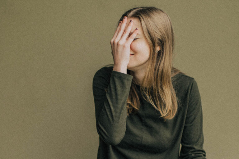 woman smiling with her hand over her face