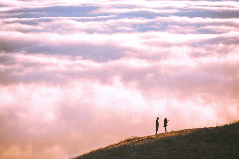 A couple on a mountainside, an endless sky in front of them.