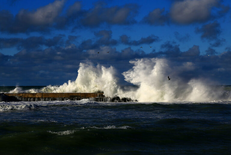 waves crash on a pier in a stormy sea