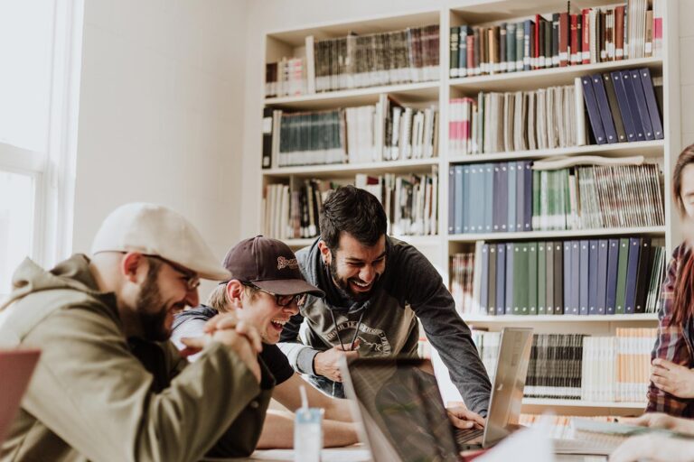 Office workers laughing at a table and looking at laptops