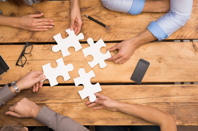 hands holding large puzzle pieces on a desktop