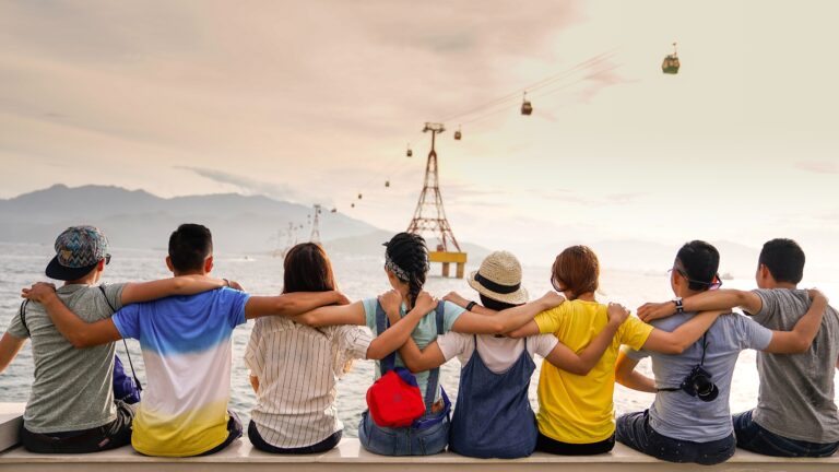 a group of people with arms resting on each other sitting with their backs turned