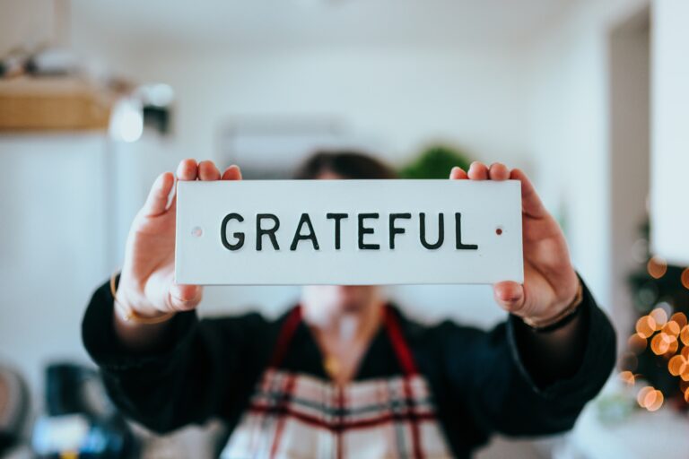 a person holding a small sign with the text "Grateful"