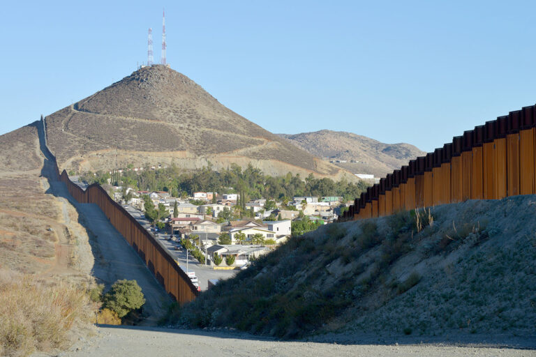 border wall with houses on one side