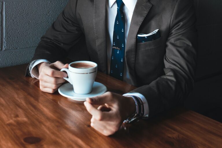 person in a suit sitting with a cup of coffee