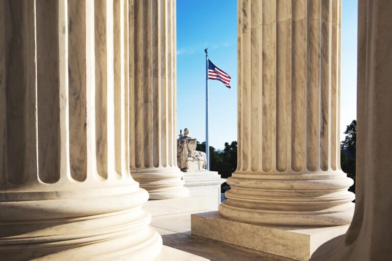 Marble columns of the supreme court building, USA flag in background