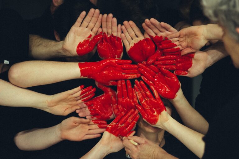 a group of people joining hands with a red heart painting on top