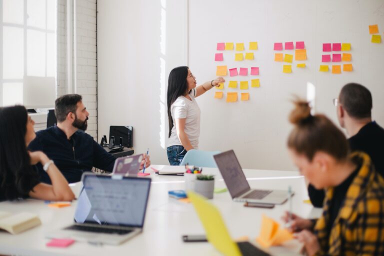 woman placing sticky notes on a white board