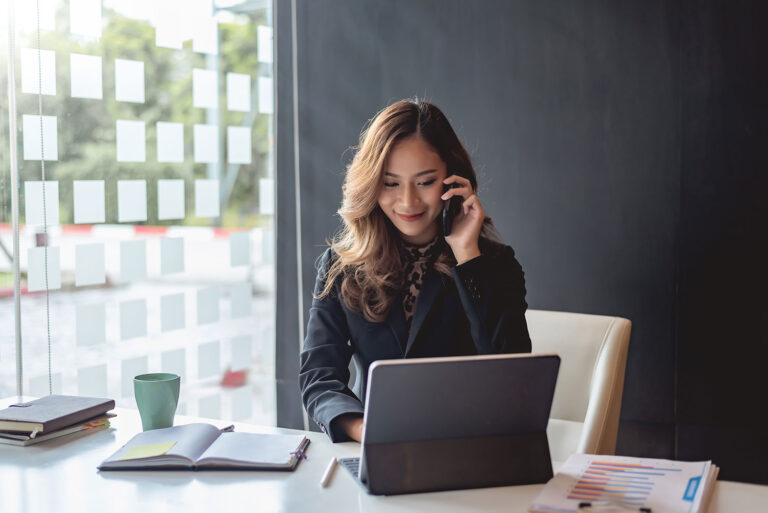 young woman looking at laptop while talking on the phone