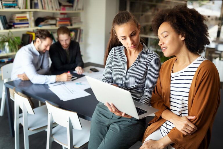 two women share a laptop