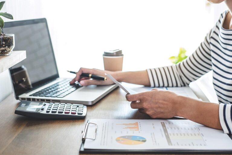 Female accountant analyzing financial graph data with calculator