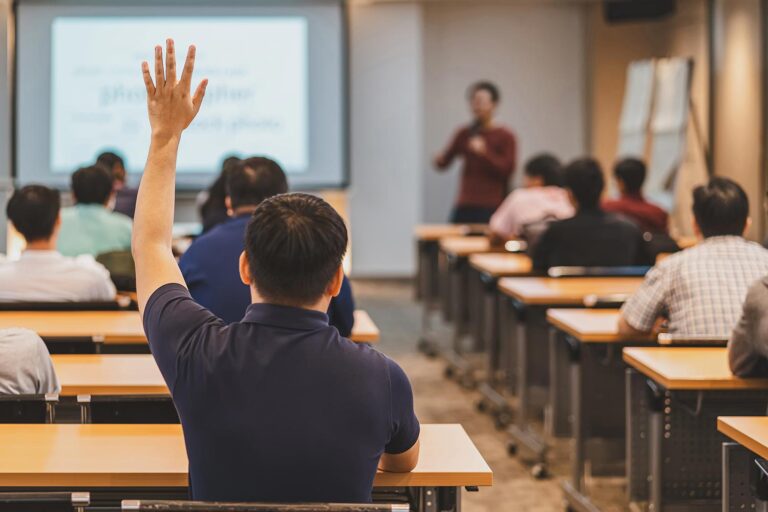 Rear view of Audience in raise hand up response for answer the question in the meeting room or conference hall over asian speaker on the stage,