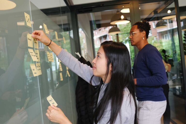 Employees putting post-its on a glass partition