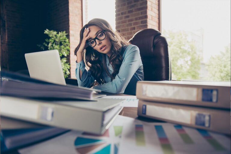 Businesswoman at a cluttered desk looking stressed