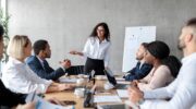 a group of business professionals talk around a meeting table