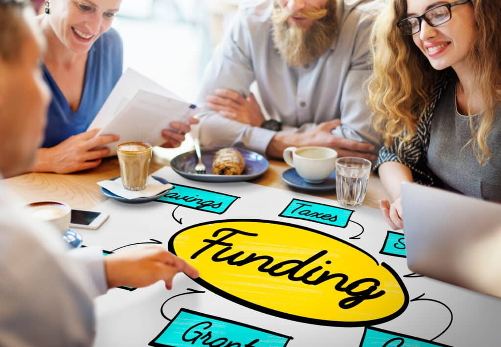 A group of people sitting around a table drawing a funding strategy