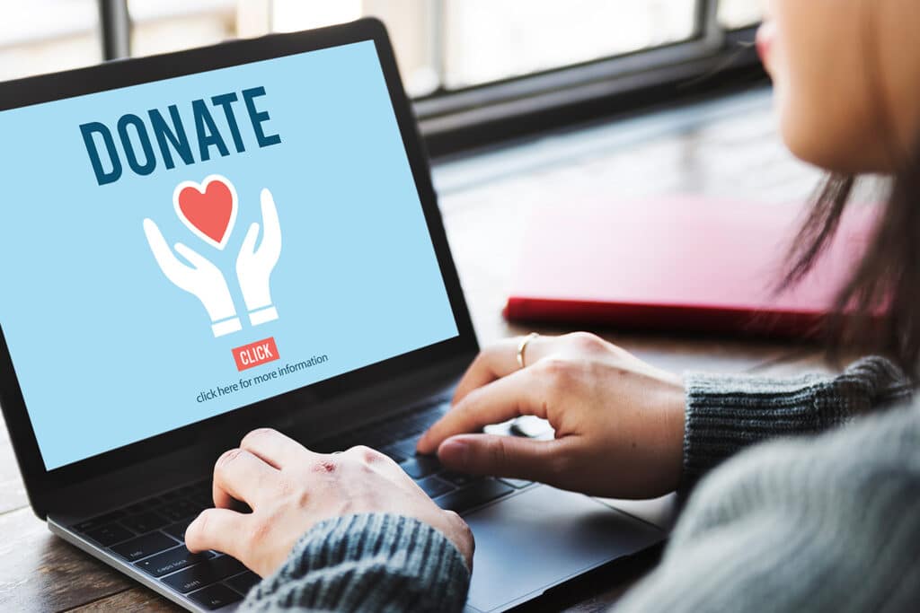 person looking at a laptop screen that reads "donate" to illustrate nonprofit fundraising 