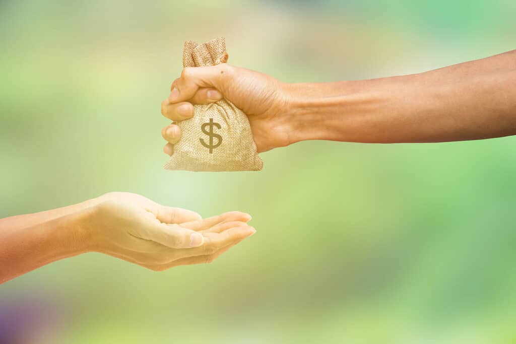 one person handing a bag of money to another person to illustrate nonprofit fundraising 