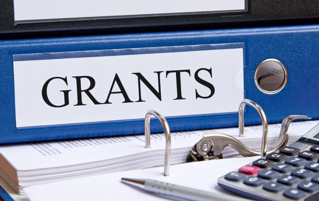  blue binder on desk in the office with the word Grants written on it to illustrate nonprofit fundraising 