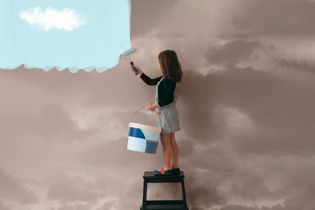 a girl on a step ladder paints a sky wall