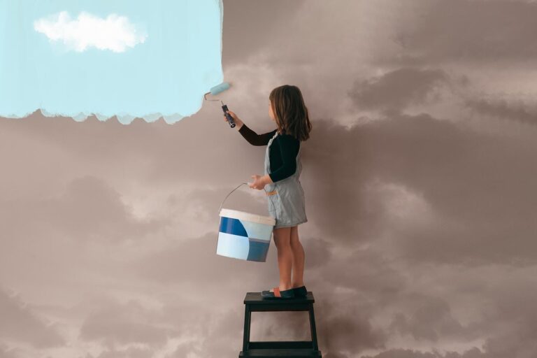 a girl on a step ladder paints a sky wall