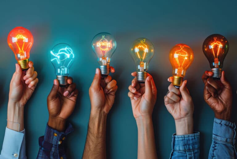 a group of hands holding up light bulbs