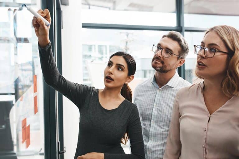 people looking at notes on a glass board