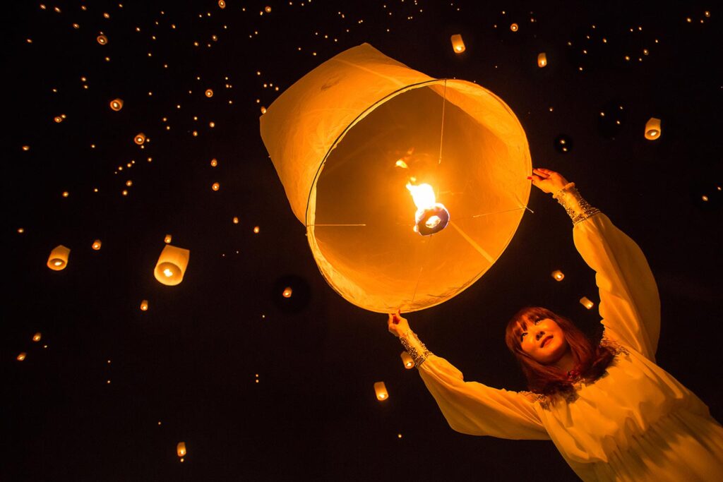 Person letting go of a glowing floating paper lantern